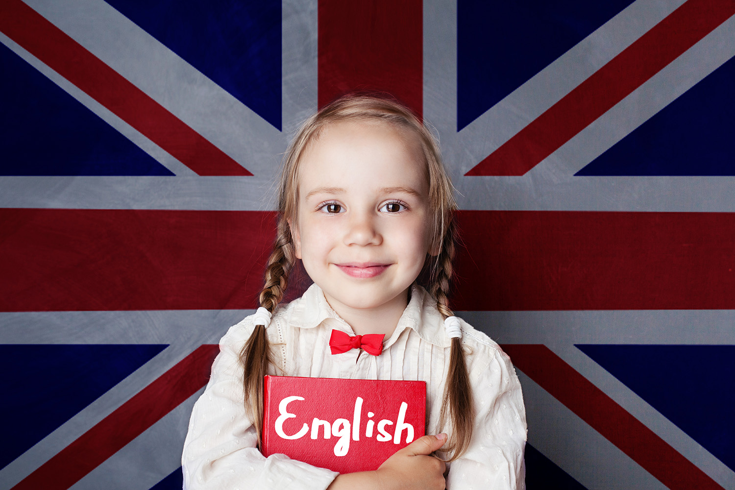 English concept with little girl student with book against the UK flag background. Learn english language